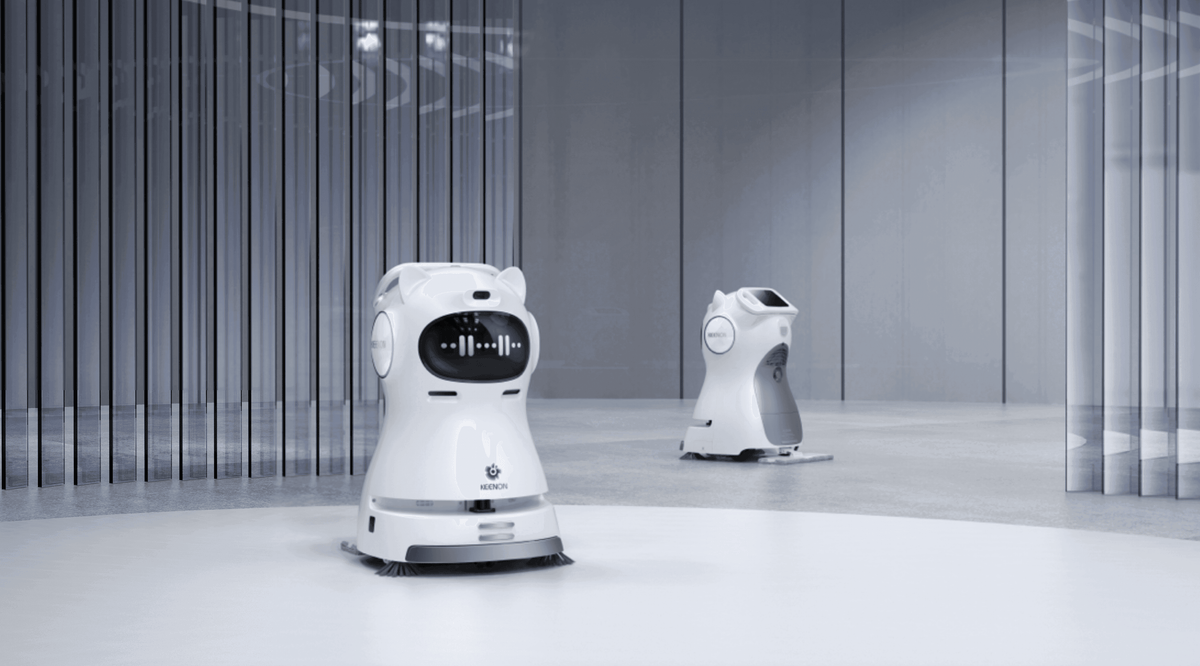 Two Kleenbot C30 cleaning robots operating in a modern commercial space, demonstrating their autonomous cleaning and smart navigation features.