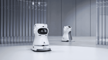 Two Kleenbot C30 cleaning robots operating in a modern commercial space, demonstrating their autonomous cleaning and smart navigation features.