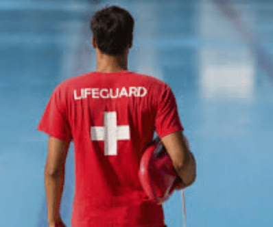 Male lifeguard in red uniform holding rescue tube beside a pool during Pool Lifeguard Certification Course. Ideal for lifeguard training services.